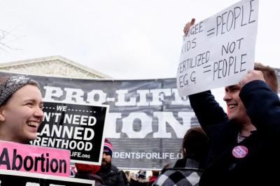 An anti-abortion demonstrator (L) and a pro-choice counter-protester (R) laugh together as the annual March for Life concludes at the Supreme Court.