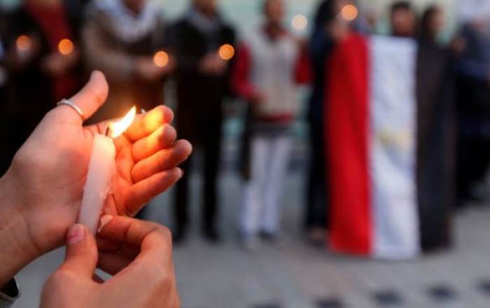 A woman holds a candle as people protest against the twin attacks on Christian churches in Egypt, in Tunis,Tunisia, April 10, 2017.