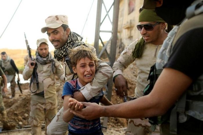 A boy cries out as Iraqi soldiers help him away from the front line during a fierce gun battle with ISIS fighters.