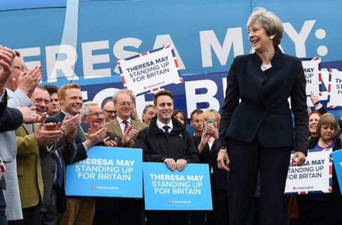 Britain's Prime Minister Theresa May addresses supporters and members of the media in front of the Conservative party's election campaign bus at an airfield north of Newcastle, England on May 12, 2017.