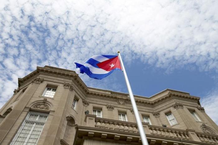 The Cuban national flag is seen raised over their new embassy in Washington, July 20, 2015.