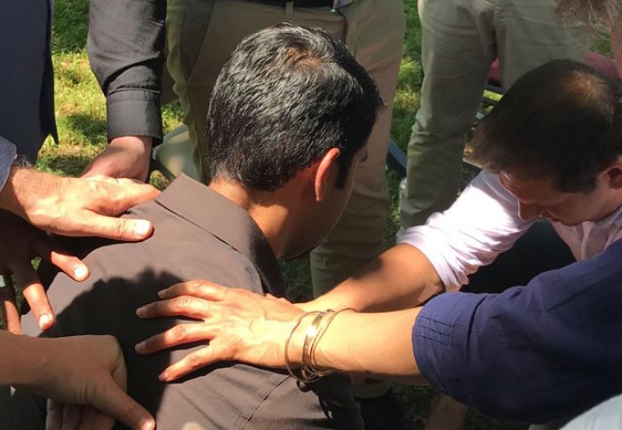 Itinerants at the annual Ravi Zacharias International Ministries team meeting pray over apologist Nabeel Qureshi, who was diagnosed with advanced stomach cancer in 2016.