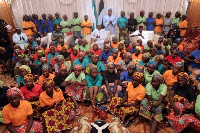 Nigeria's President Muhammadu Buhari (seated at center behind the girls) and other top Nigerian officials applaud as they welcome a group of Chibok girls, who were held captive for three years by the millitant group Boko Haram, in Abuja, Nigeria, on May 7, 2017.