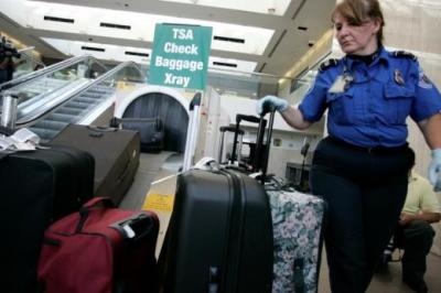A TSA worker loads suitcases at the checked luggage security screening station at Los Angeles International Airport.