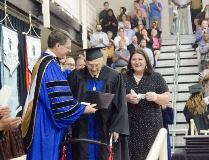 Shorter University President Don Dowless presents the Rev. Horace Sheffield with his degree on May 5, 2017. His daughter, Amanda Brannock, watches with emotion.