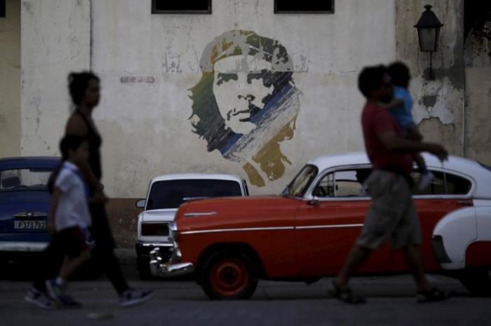 People walk past a painting of late revolutionary hero Ernesto ''Che'' Guevara in Havana, March 16, 2016.