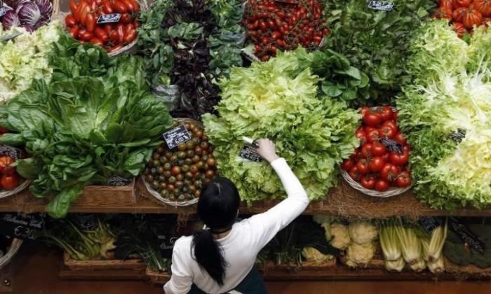 An employee arranges price tags at a vegetables work bench during the opening day of upmarket Italian food hall chain Eataly's flagship store in downtown Milan, March 18, 2014.