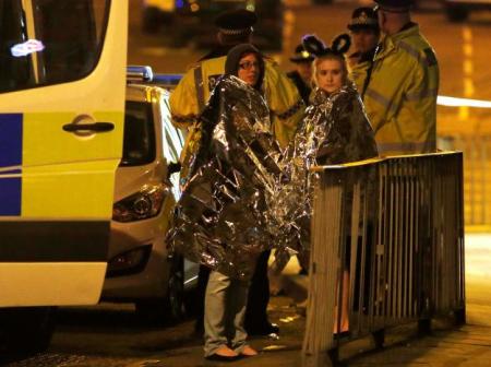 Two women wrapped in thermal blankets stand near the Manchester Arena, where U.S. singer Ariana Grande had been performing, in Manchester, northern England, Britain, May 23, 2017.