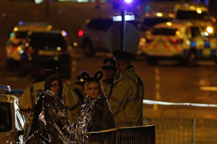 Two women wrapped in thermal blankets look on near the Manchester Arena, where U.S. singer Ariana Grande had been performing, in Manchester, northern England, Britain May 23, 2017.