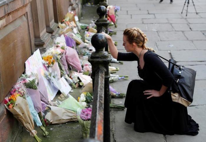 A woman lays flowers for the victims of the Manchester Arena attack, in central Manchester, Britain May 23, 2017.