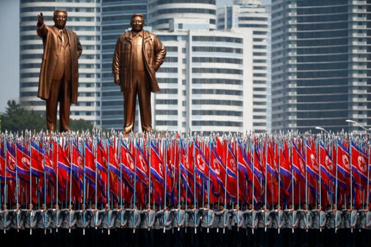 People carry flags in front of statues of North Korea founder Kim Il Sung (L) and late leader Kim Jong Il during a military parade marking the 105th birth anniversary Kim Il Sung, in Pyongyang April 15, 2017.