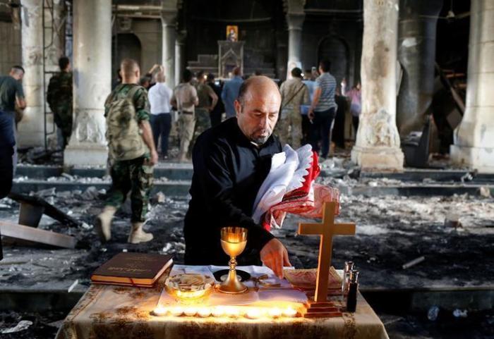 An Iraqi priest prepares for Sunday mass at the damaged Grand Immaculate Church in Qaraqosh, near Mosul, Iraq on Oct. 30, 2016 after it was recaptured from ISIS.