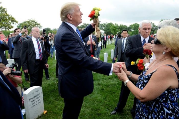 U.S. President Donald Trump holds flowers and gestures towards the sky as he greets a mother who has lost a son in recent conflicts, along with Vice President Mike Pence (background) at Section 60 of Arlington National Cemetery as part of Memorial Day observance, Arlington,Virginia, U.S., on May 29, 2017.