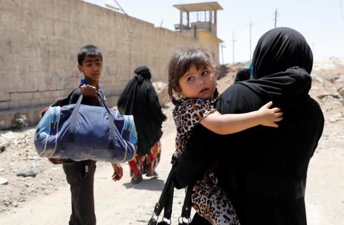 A woman carries her child as she walks to a safer area with other displaced residents, due to fighting between Iraqi forces and Islamic State militants in western Mosul's al-Zanjili district in Iraq June 7, 2017