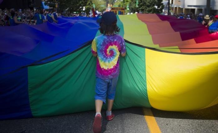 A boy holds a large rainbow tarp while taking part in Vancouver's 35th annual Pride Parade in Vancouver, British Columbia, on August 4, 2013.