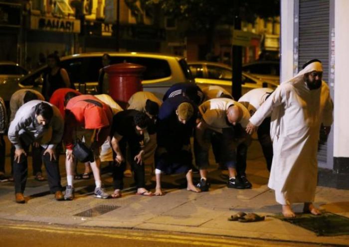 Men pray after a vehicle collided with pedestrians near a mosque in the Finsbury Park neighborhood of North London, Britain June 19, 2017.