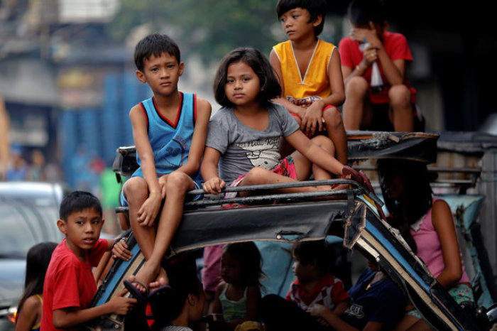 Children watch as policemen investigate near the body of a woman killed by unknown gunmen at the market in a port area of Manila, Philippines, on October 28, 2016.