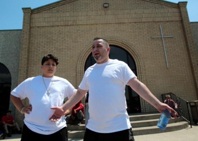 Chaldean-American Mike Kajy stands with his son Miguel as he talks about the seizure of his brother and cousin on Sunday by Immigration and Customs Enforcement agents during a rally outside the Mother of God Chaldean church in Southfield, Michigan, U.S., June 12, 2017.