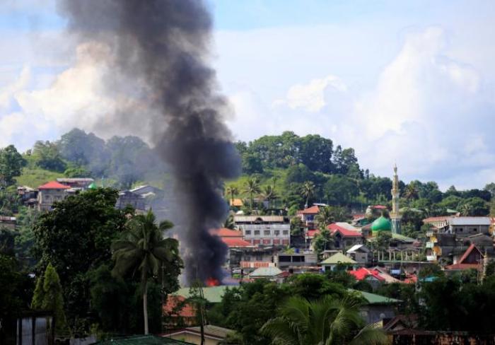 Smoke billowing from a burning building is seen as government troops continue their assault on insurgents from the Maute group, who have taken over large parts of Marawi City, Philippines.
