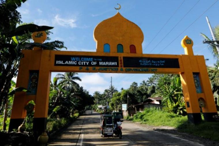 A motorbike drives pass an arch with a welcome message at the entrance of Marawi City where Philippines army troops continue their assault against insurgents from the Maute group, in Malawi City, Philippines, June 28, 2017.