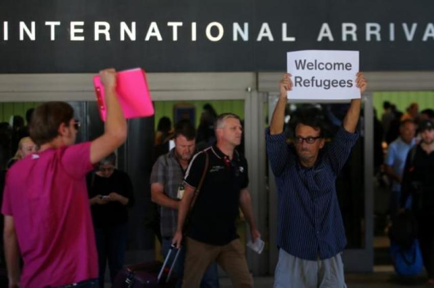Retired engineer John Wider, 59, is greeted by a supporter of U.S. President Donald Trump as he holds up a sign reading "Welcome Refugees" at the international arrivals terminal at Los Angeles International Airport in Los Angeles, California, U.S., June 29, 2017.