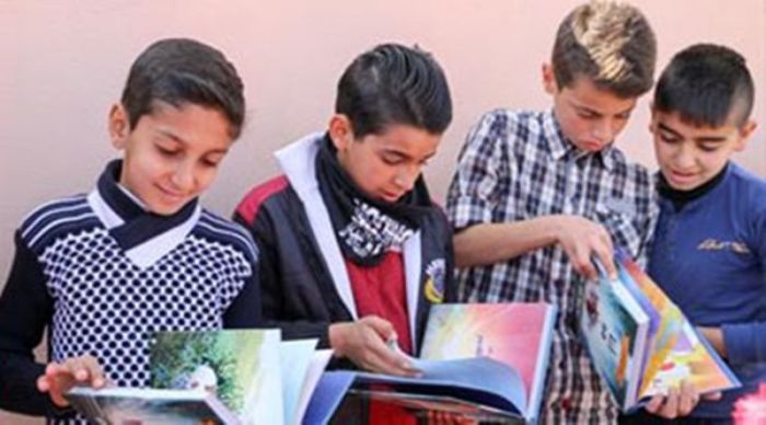 Iraqi children check the pages of Christian books distributed to them by the Christian charity Open Doors.