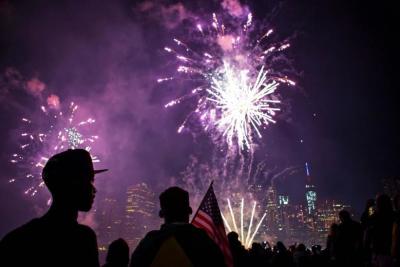 The skyline of lower Manhattan is seen as spectators watch Macy's Fourth of July fireworks explode over the East River in New York July 4, 2014.