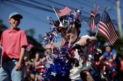 A boy wears decorations as he rides his bicycle through Barnstable Village, on Cape Cod during the annual Independence Day parade celebrations in Barnstable, Massachusetts, U.S., July 4, 2016.