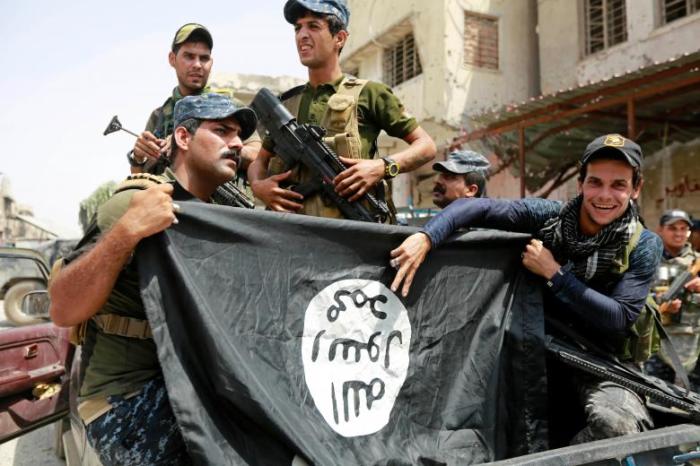 Iraqi Federal Police members hold an Islamic State flag, which they pulled down during fighting in Mosul in July 2017.