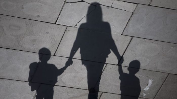 A woman and children cast their shadows as they stroll in the sunshine on the Southbank in London, Britain September 19, 2015.