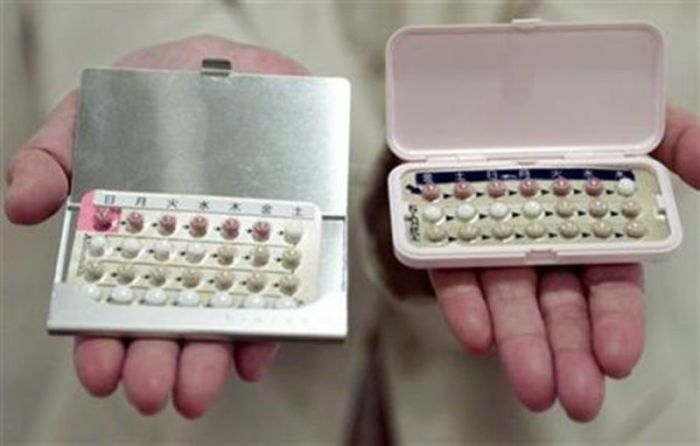 A pharmacist holds two packs of birth control pills.