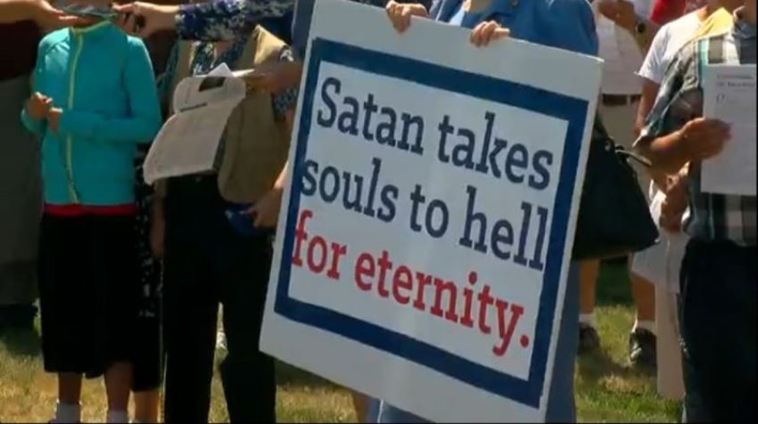 Over 100 people protest on July 15, 2017, against a Satanic memorial at Belle Plaine, Minn., holding signs reading "Satan takes souls to Hell for eternity."