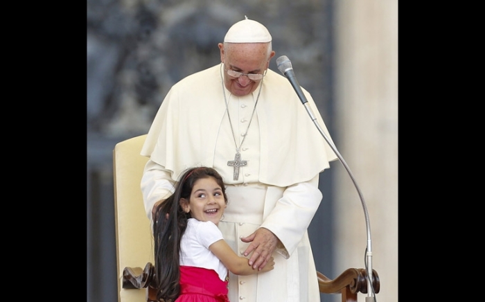 A girl smiles as she embraces Pope Francis during an audience Sunday for families participating in the pastoral conference of the diocese of Rome in St. Peter's Square at the Vatican.