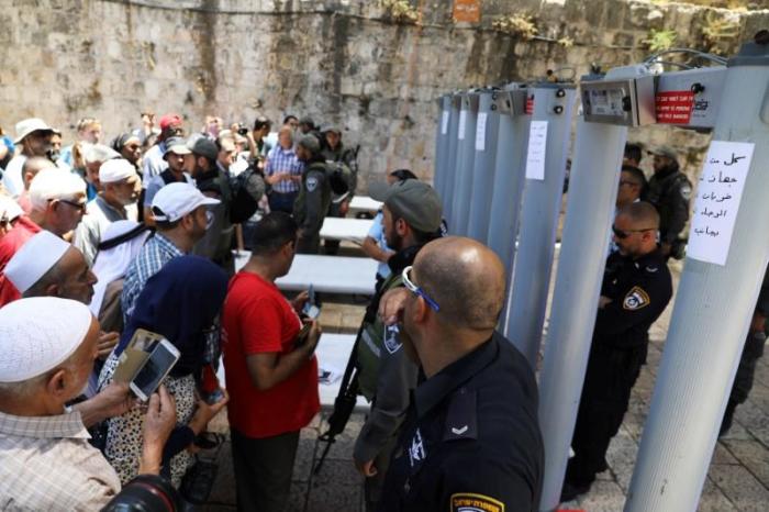 Palestinians stand in front of Israeli police officers and newly installed metal detectors at an entrance to the compound known to Muslims as Noble Sanctuary and to Jews as Temple Mount, in Jerusalem's Old City July 16, 2017.