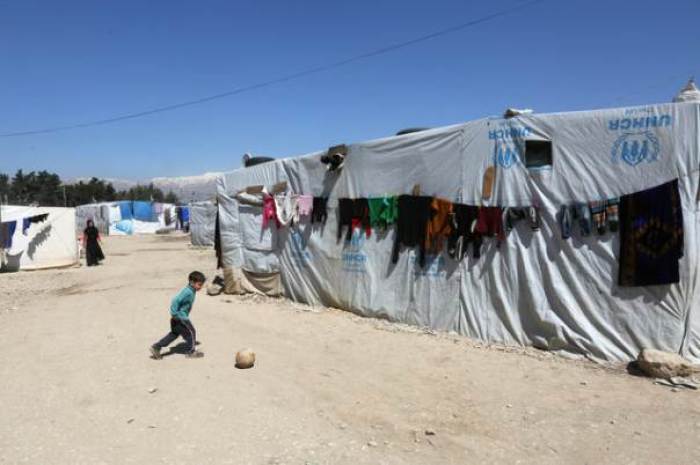 A Syrian refugee boy plays outside tents at a makeshift settlement in Bar Elias town, in the Bekaa valley, Lebanon March 28, 2017. Picture taken March 28, 2017.