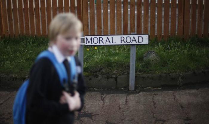 A boy passes a broken sign for Balmoral Road, the street where the former Johnnie Walker plant was located in Kilmarnock, Scotland, March 25, 2014.