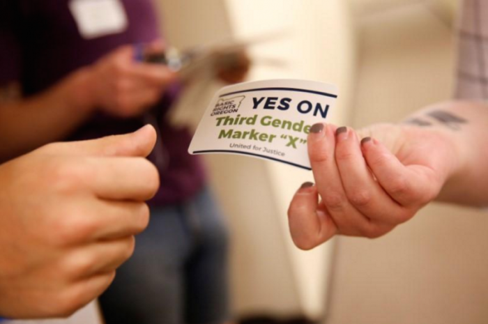 An employee of the advocacy group Basic Rights Oregon hands out stickers during an Oregon Driver and Motor Vehicle department public hearing on the rights of transgender people as the state considers adding a third gender choice to driver's licenses and identification cards, in Portland, Oregon, May 10, 2017.