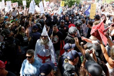 Riot police protect members of the Ku Klux Klan from counter-protesters as they arrive to rally in opposition to city proposals to remove or make changes to Confederate monuments in Charlottesville, Virginia, August 12, 2017.