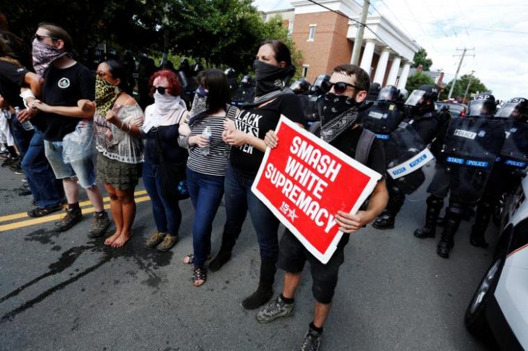 Counter-protesters lock arms in the middle of a street as police try to disperse them, after members of the Ku Klux Klan rallied in support of Confederate monuments in Charlottesville, August 12, 2017.