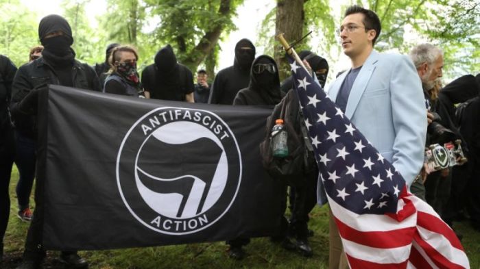 A right-wing protester walks past a group of Antifa activists during an alt-right rally in Portland, Oregon.