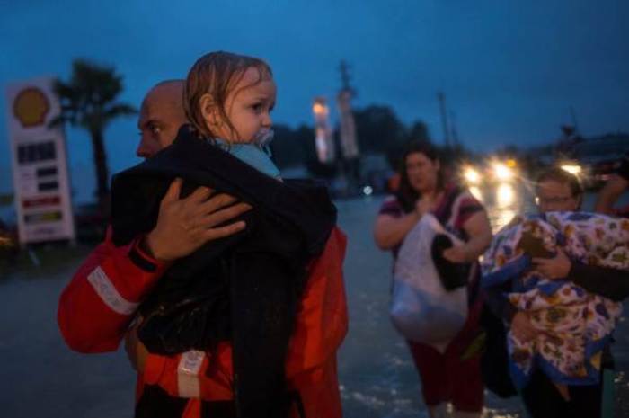 A policeman carries a young girl as her family follows after they fled their home due to floods caused by Tropical Storm Harvey along Tidwell Road in east Houston, Texas, U.S. August 28, 2017.