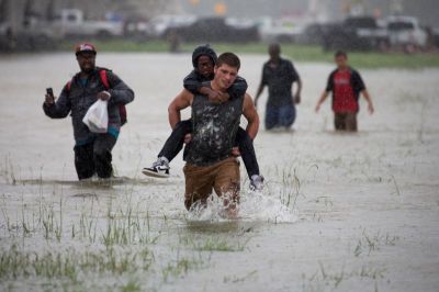 A man wades through flood waters from Tropical Storm Harvey while helping evacuate a boy in east Houston, Texas, U.S. August 28, 2017.