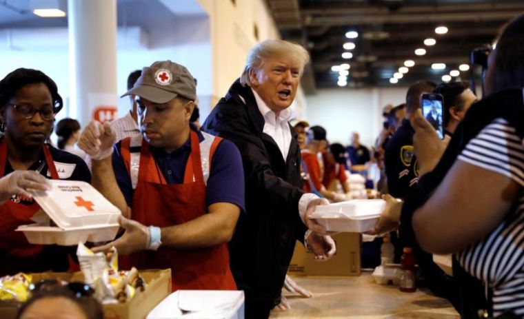 U.S. President Donald Trump helps volunteers hand out meals during a visit with flood survivors of Hurricane Harvey at a relief center in Houston, Texas, U.S., September 2, 2017.