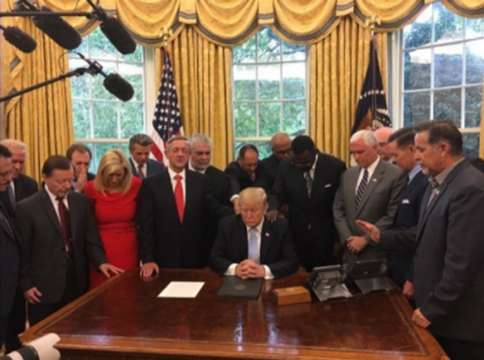 Members of President Donald Trump's evangelical advisory board pray with him in the Oval Office.