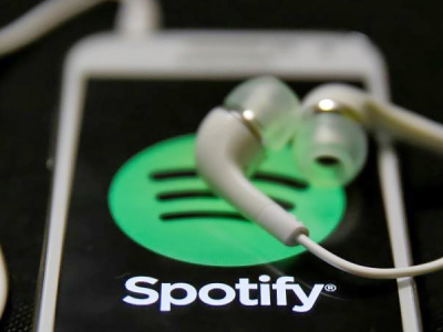 Earphones are seen on top of a smart phone with a Spotify logo on it, in Zenica.