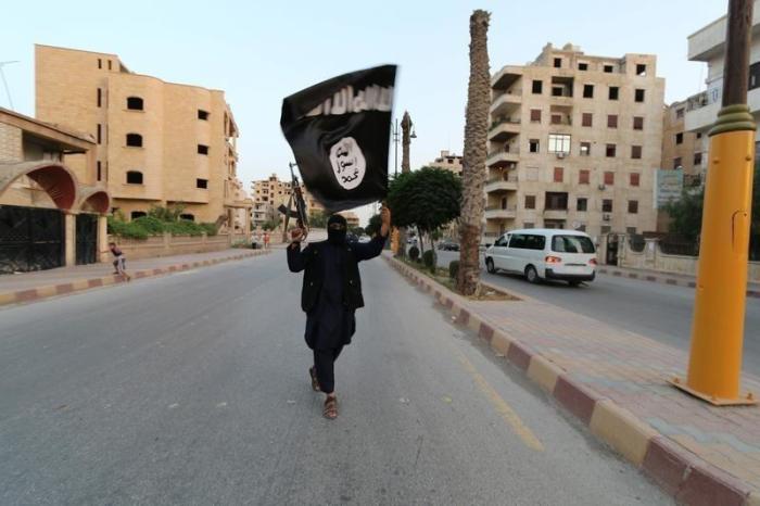 A member loyal to the Islamic State in Iraq and the Levant waves an ISIS flag in Raqqa, on June 29, 2014.