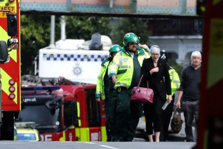 An injured woman is led away after an incident at Parsons Green underground station in London, Britain, September 15, 2017.