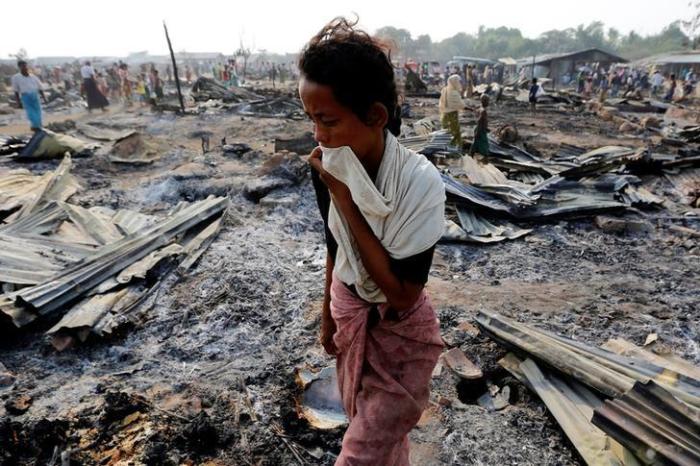 A woman walks among debris after fire destroyed shelters at a camp for internally displaced Rohingya Muslims in the western Rakhine State near Sittwe, Myanmar, on May 3, 2016.