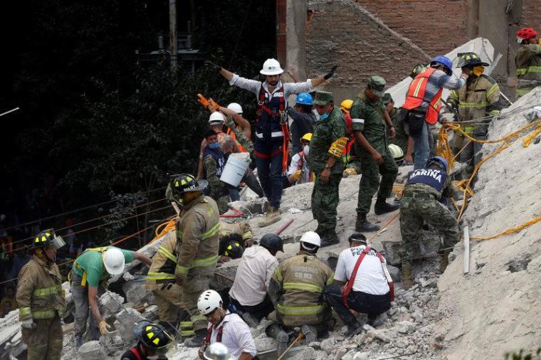 A rescue worker motions for everybody to be quiet as they are searching for people under the rubble of a collapsed building after an earthquake hit Mexico City, Mexico, September 19, 2017.
