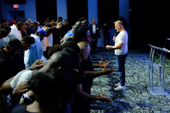 Pastor Ron Carpenter Jr.(with mic), of Redemption World Outreach Center in Greenville, South Carolina, prays with a multiracial group of men.